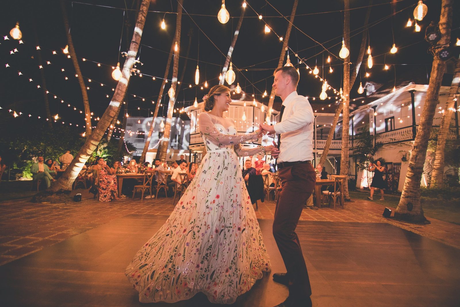 Couple dancing at dusk under string lights in a courtyard