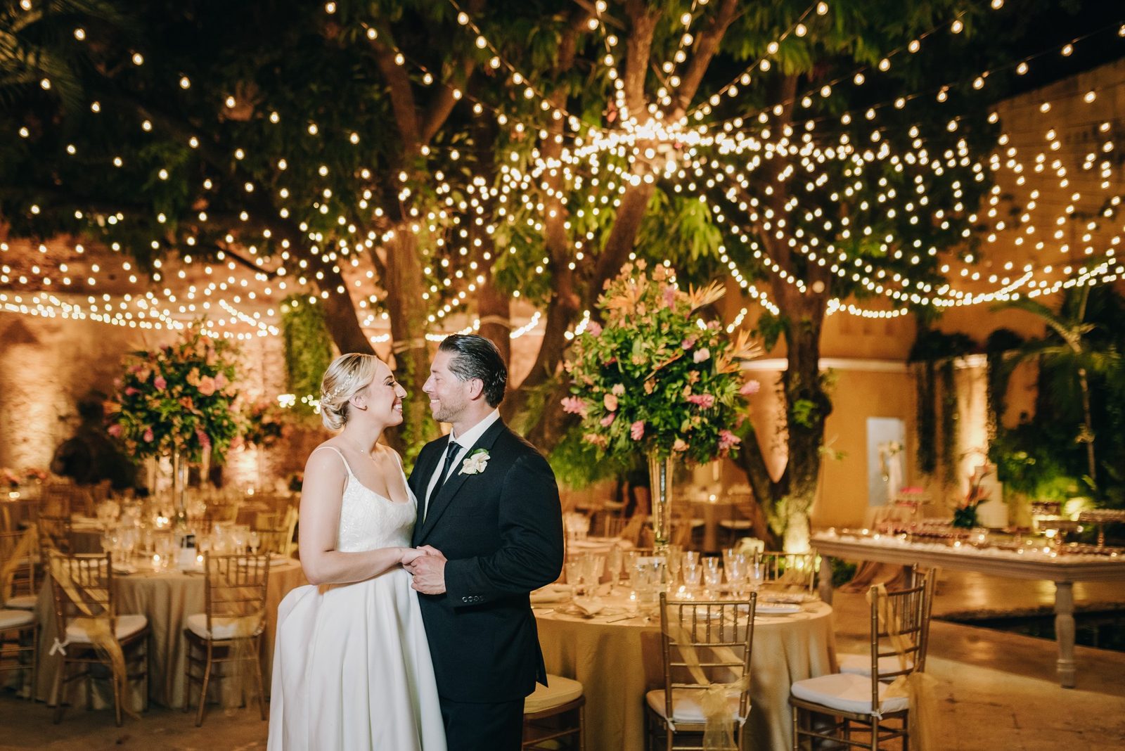 First dance under strings of Edison bulbs between palm trees