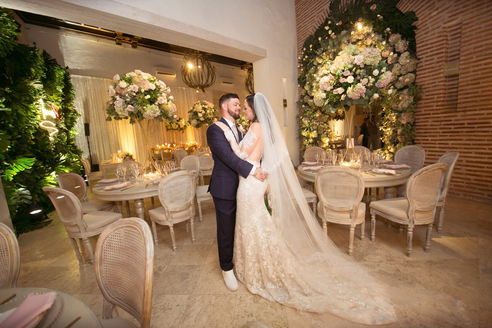 Couple at a garden reception with an illuminated green arch and dining tables