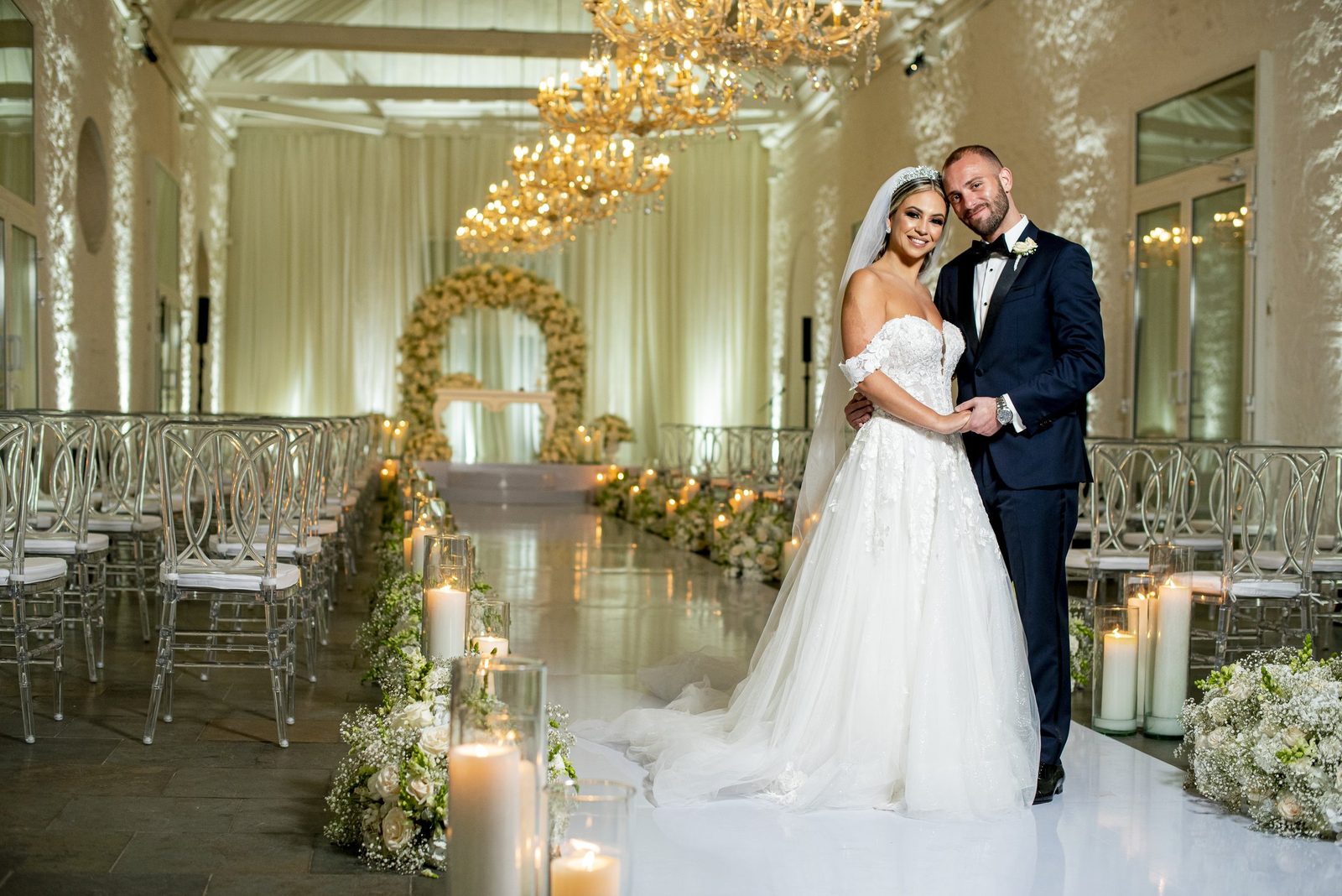 Bride and groom at an all-white ceremony with a flower arch