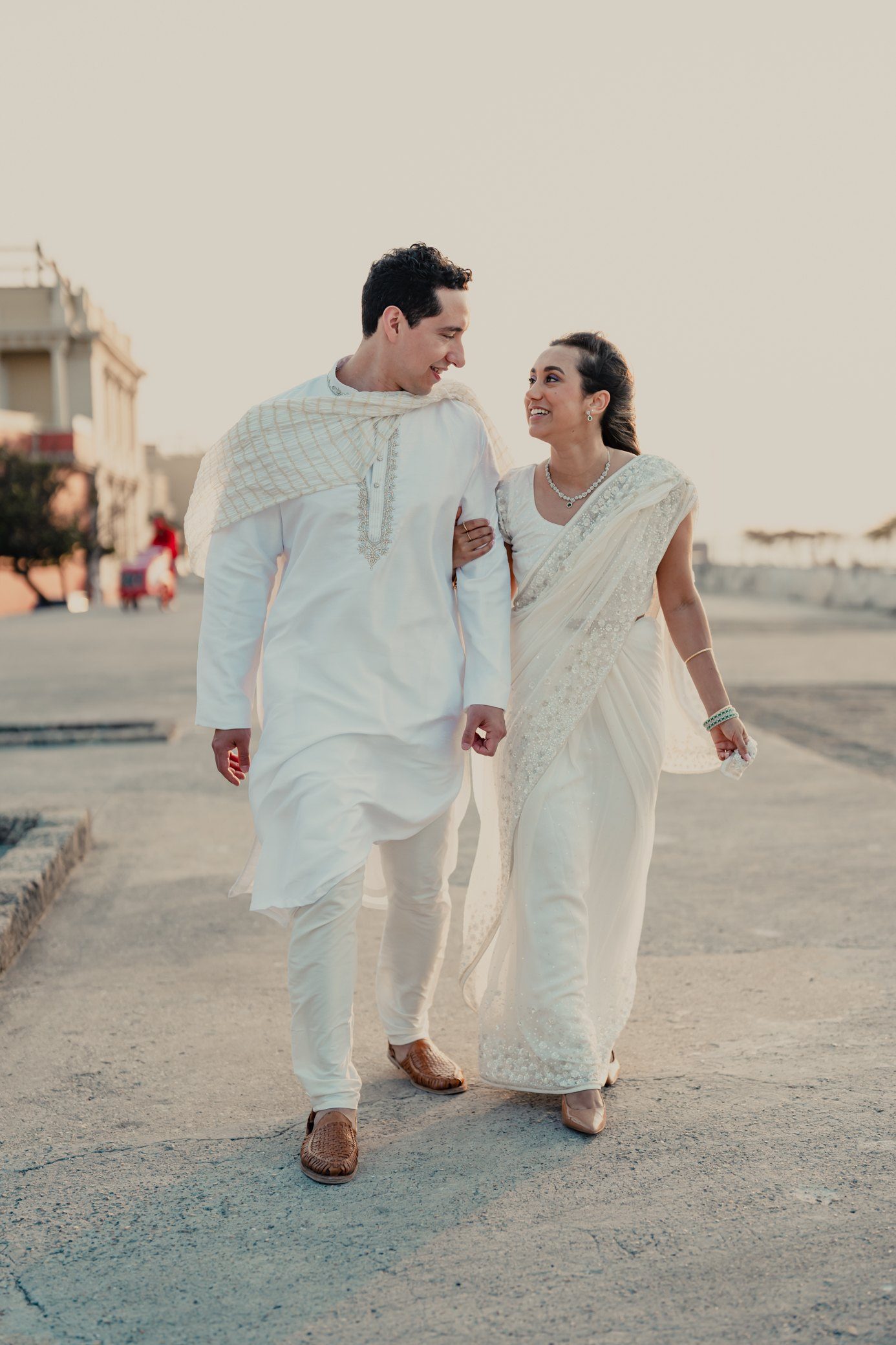 Couple in white walking along the sea wall of Cartagena at sunset