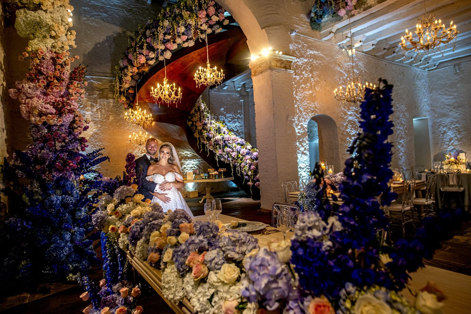 Bride and groom on a grand staircase covered in blue and white flowers, Cartagena