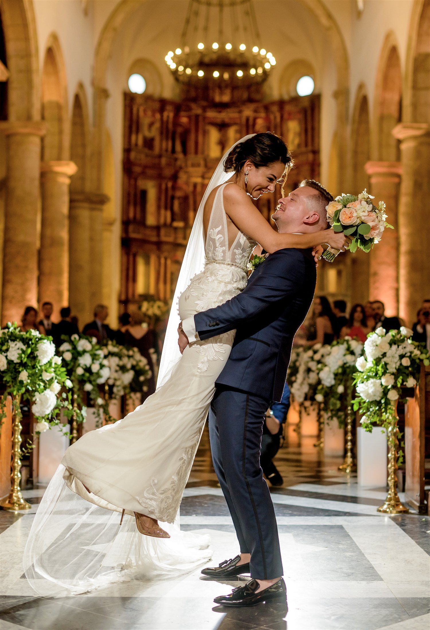 Groom lifting the bride in a candlelit historic church