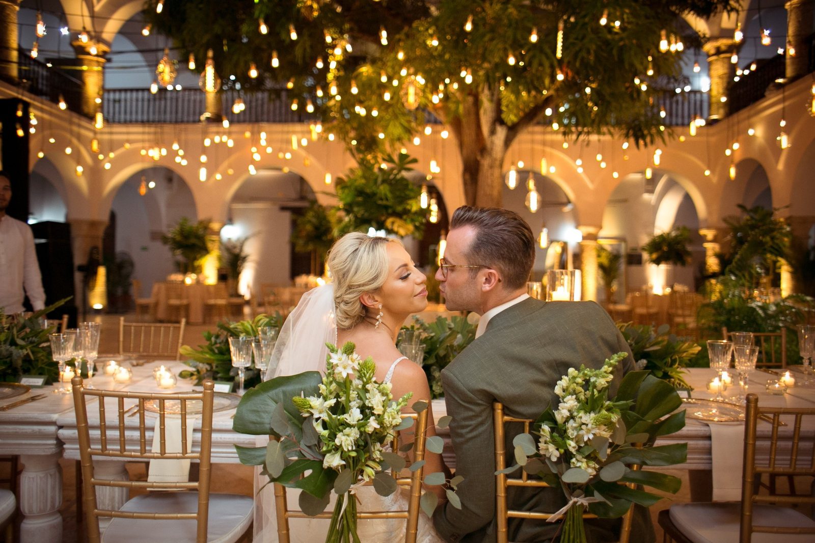 Couple kissing at the table under hanging lights in a colonial courtyard
