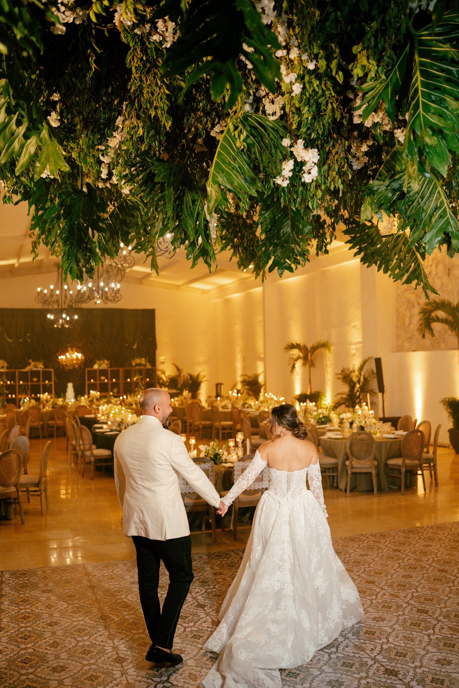 Couple dancing in a white hall decorated with greenery